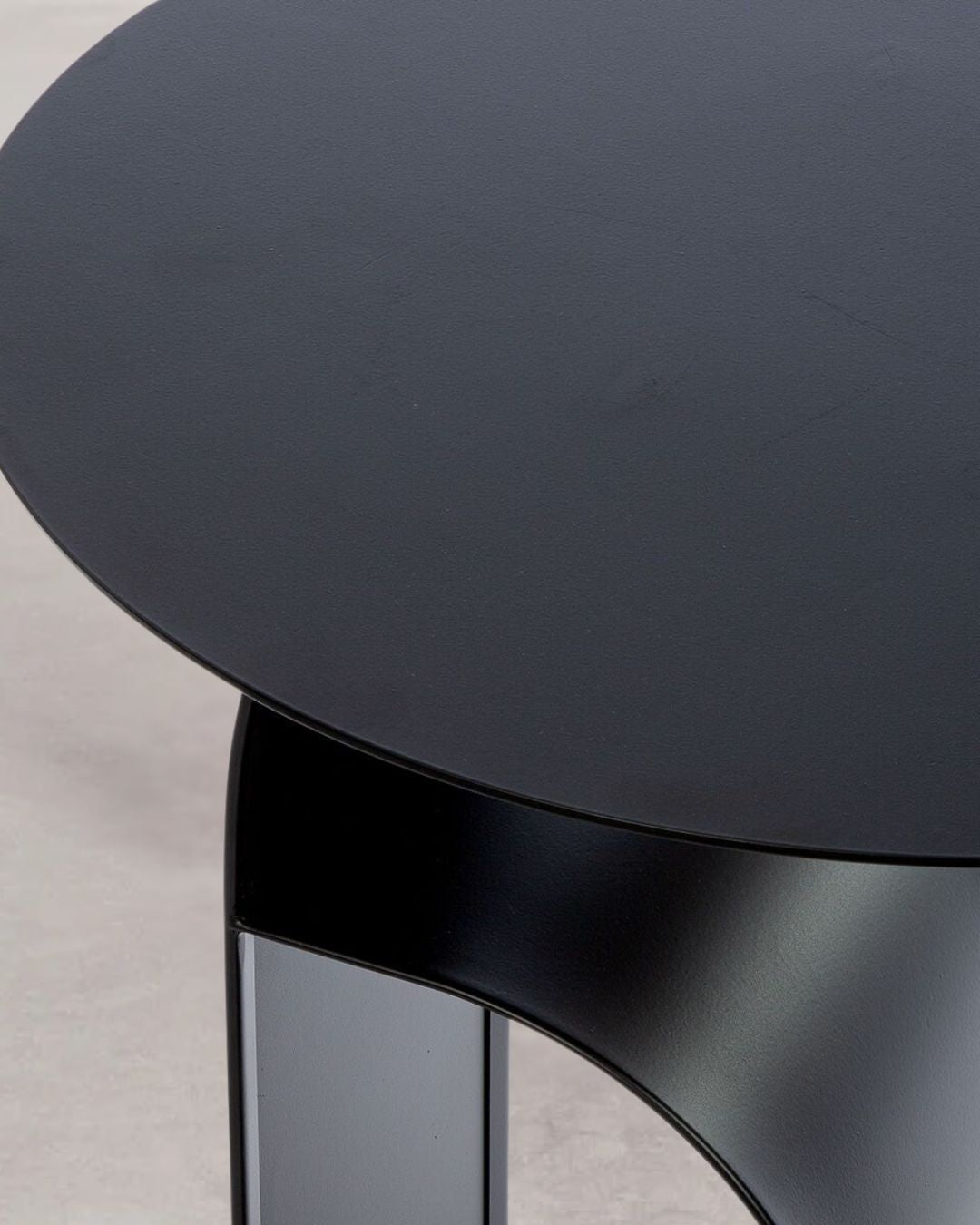 Detailaufnahme der glatten Metalloberfläche des schwarzen Beistelltisches "Memphis".