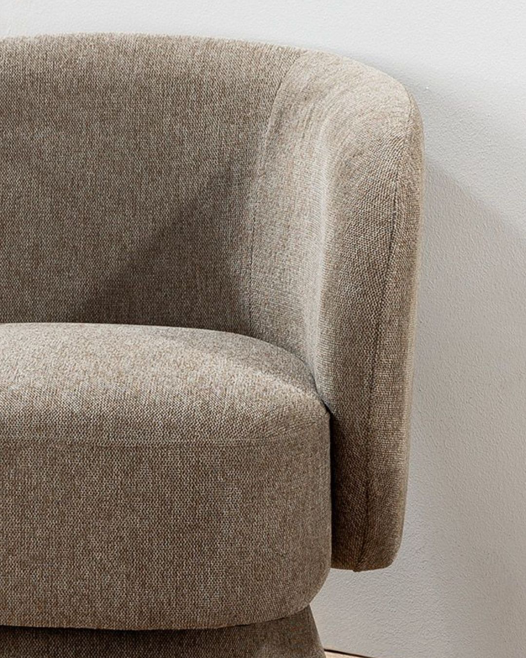 Detailansicht des grauen "Rotunda" Sessels, der sich durch seine neutrale Farbpalette und eleganten Stoffbezug auszeichnet.